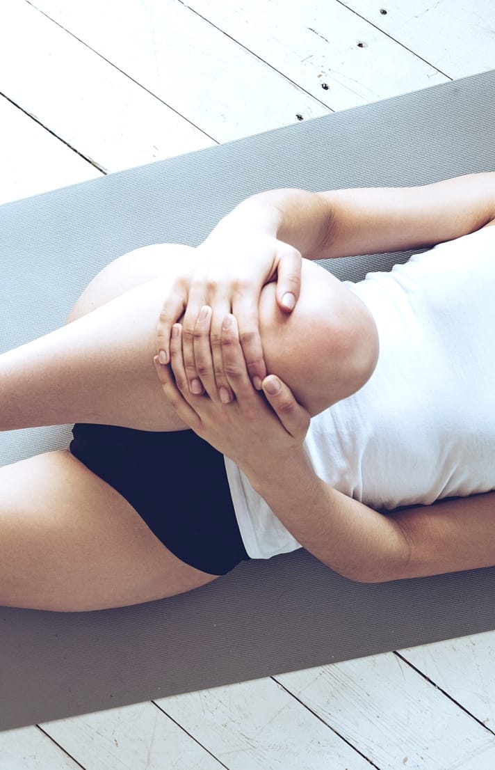 Closeup photo of woman stretching, pulling knee to chest