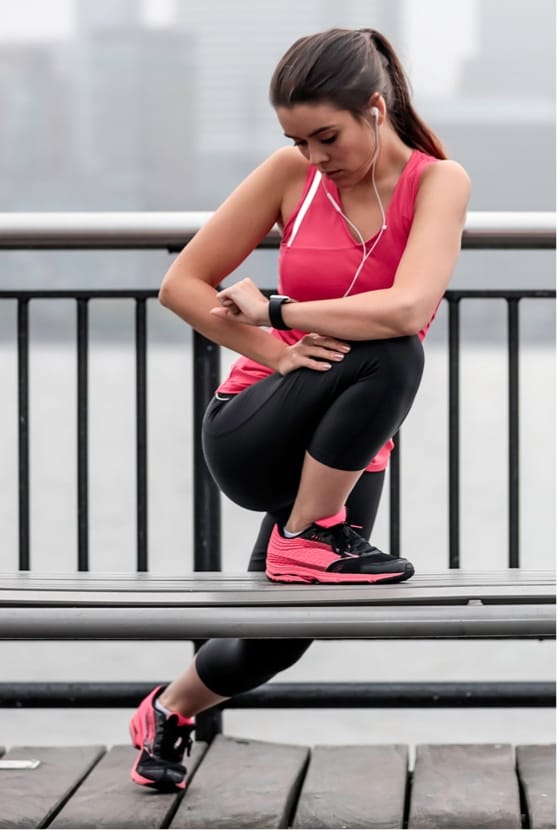 Woman stretching her hip on a bench outside