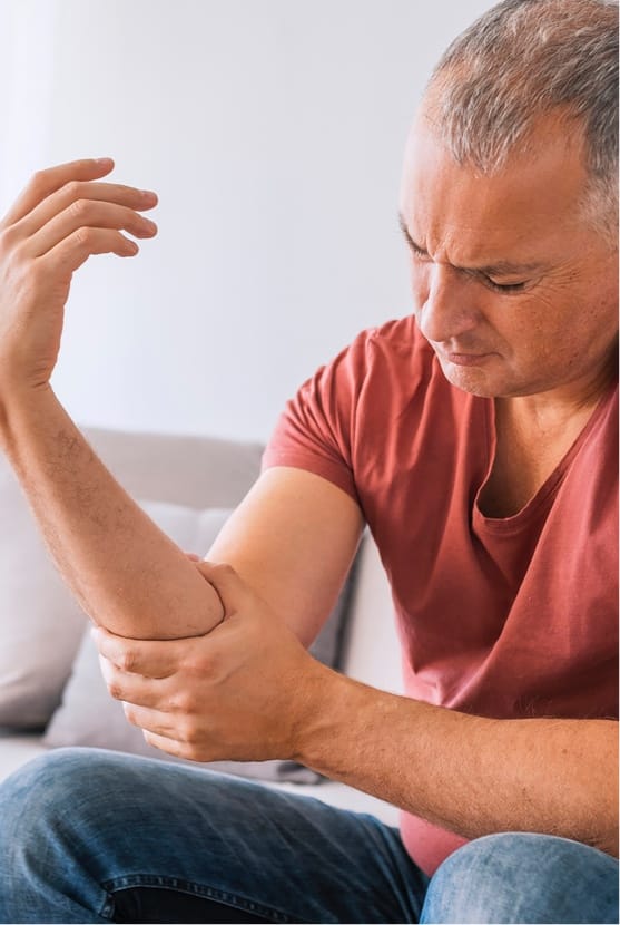 Middle-aged man grabbing elbow in discomfort