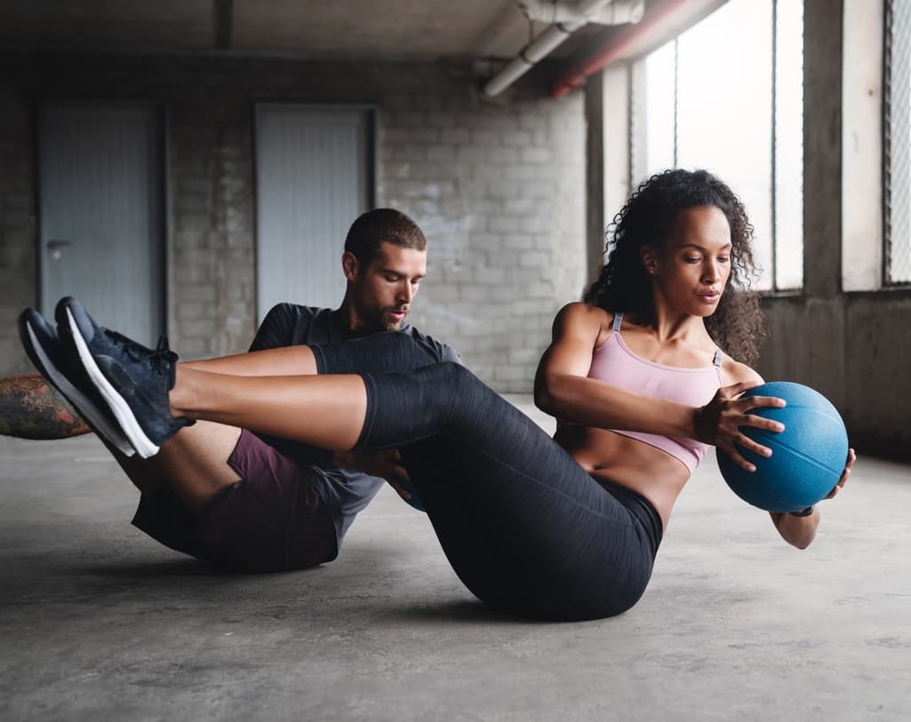 Man and woman doing core exercises in a gym